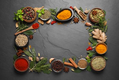 Frame of different herbs and spices on black table, flat lay. Space for text