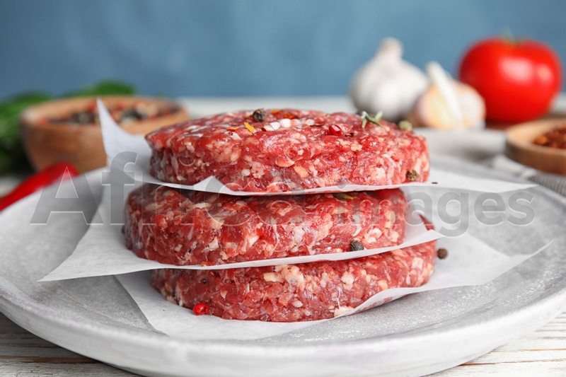 Raw meat cutlets for burger on white wooden table, closeup