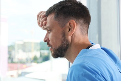 Exhausted doctor looking out of window in hospital