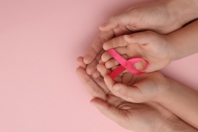 Woman and child holding pink ribbon on color background, top view with space for text. Breast cancer awareness