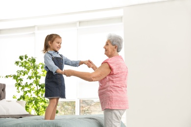 Photo of Cute girl and her grandmother playing together at home