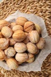Photo of Bowl of delicious nut shaped cookies on wicker mat, top view