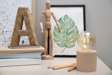 Modern night lamp, books and decor on table near grey wall. Space for text