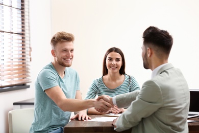 Insurance agent shaking hands with client in office