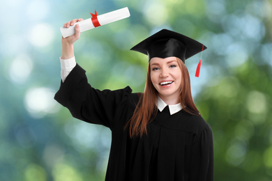 Happy student with graduation hat and diploma on blurred background