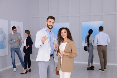 Couple with glasses of champagne at exhibition in art gallery