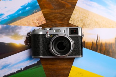 Vintage photo camera and beautiful printed pictures on wooden table, flat lay. Creative hobby