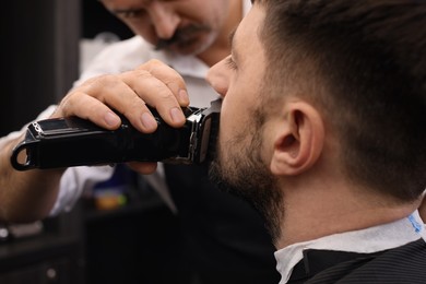 Professional hairdresser working with client in barbershop, closeup