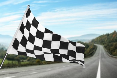 Image of Checkered racing finish flag and asphalt road outdoors