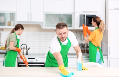 Team of professional janitors in uniform cleaning kitchen