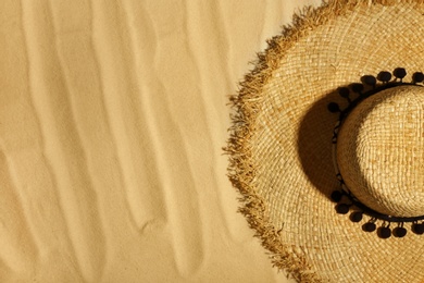 Straw hat on beach sand, top view. Space for text