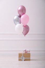 Two gift boxes and balloons near white wall in room