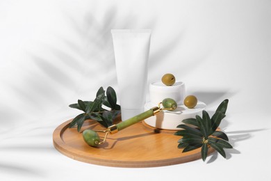 Photo of Cosmetic products, olives and jade roller on white background