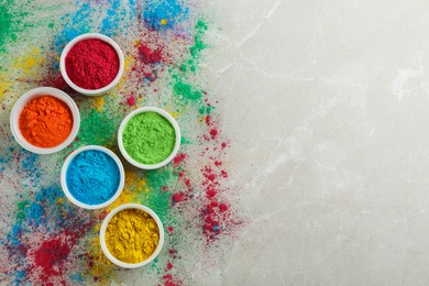 Colorful powder dyes on light marble background, flat lay with space for text. Holi festival