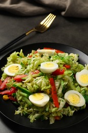 Delicious salad with Chinese cabbage and quail eggs served on black table, closeup
