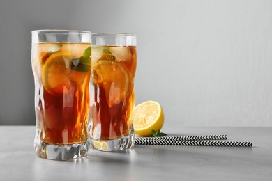 Glasses of refreshing iced tea on table against grey background. Space for text