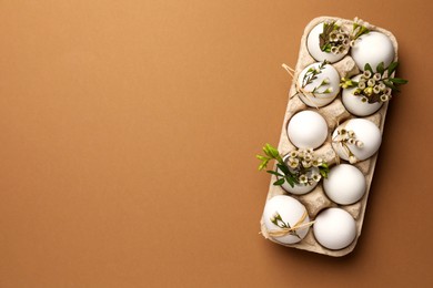 Photo of Happy Easter. Festive composition with eggs and floral decor on brown background, top view. Space for text