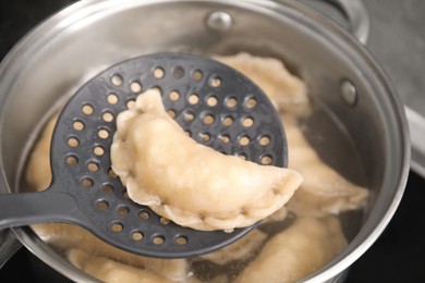 Photo of Dumpling (varenyk) with cottage cheese on skimmer over pot, closeup