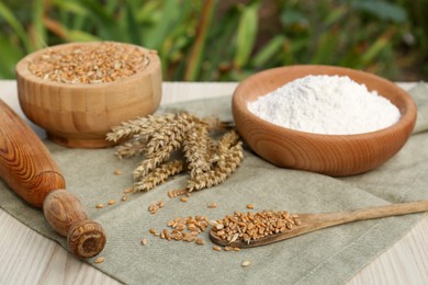 Photo of Wheat grains, flour and spikelets on table outdoors