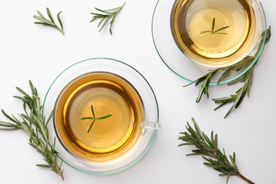 Cups of aromatic herbal tea with rosemary on white table, flat lay