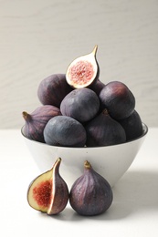 Whole and cut tasty fresh figs on white table
