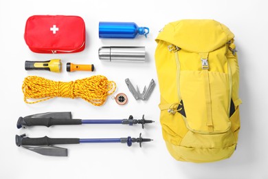 Trekking poles and other hiking equipment on white background, top view