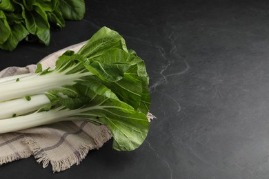 Fresh green pak choy cabbages on black table, space for text