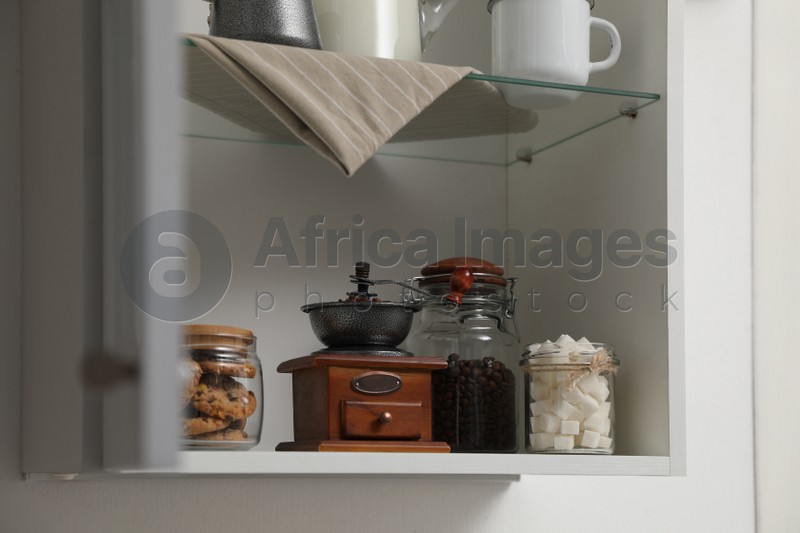 Vintage coffee grinder, sugar and cookies on shelving unit in kitchen