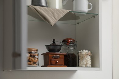 Photo of Vintage coffee grinder, sugar and cookies on shelving unit in kitchen