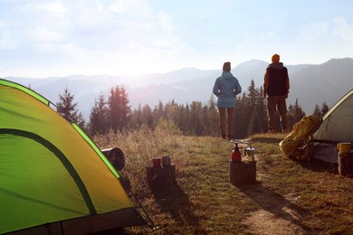 Couple enjoying beautiful mountain landscape near camping tents, back view