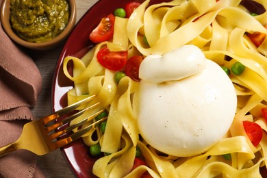 Photo of Plate of delicious pasta with burrata, peas and tomatoes on table, closeup