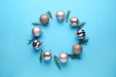 Bright festive wreath made of Christmas balls and fir branches on light blue background, top view. Space for text