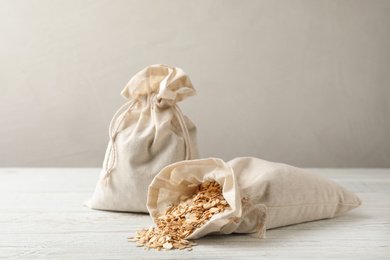Photo of Cotton eco bags with oat flakes on white wooden table