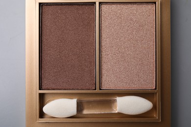 Photo of Beautiful eyeshadow palette with applicator on light gray background, top view. Professional cosmetic product