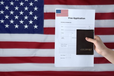 Woman holding visa application form and passport against American flag, closeup. Space for text
