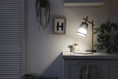 Stylish lamp and decor on white cabinet in room, space for text. Interior element