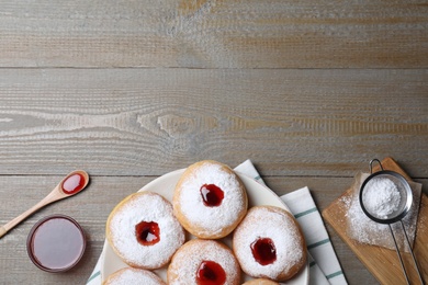 Hanukkah doughnuts with jelly and sugar powder served on wooden table, flat lay. Space for text