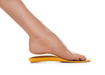 Woman fitting orthopedic insole on white background, closeup. Foot care