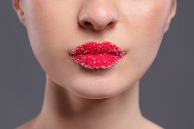 Photo of Woman with beautiful lips covered in sugar on grey background, closeup