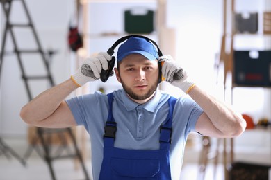 Worker wearing safety headphones indoors. Hearing protection device
