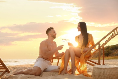 Romantic couple drinking wine together on beach at sunset