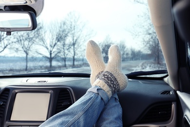 Young woman in warm socks holding her legs on car dashboard. Cozy atmosphere