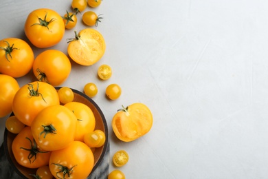 Ripe yellow tomatoes on grey table, flat lay. Space for text