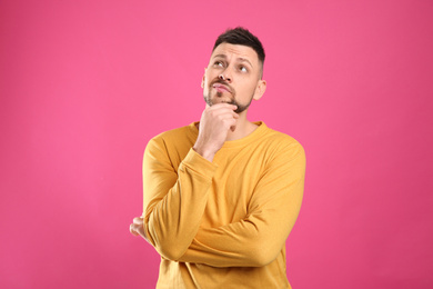 Emotional man in casual outfit on pink background