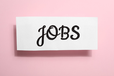 Photo of Card with word JOBS on pink background, top view. Career concept