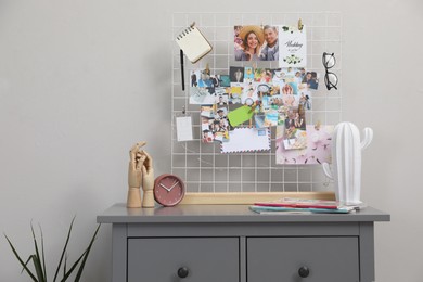 Chest of drawers with vision board and decor elements near grey wall indoors