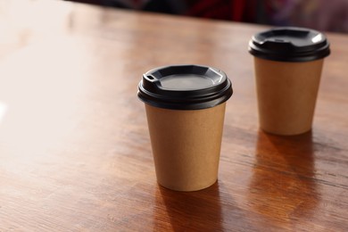 Paper coffee cups with plastic lids on wooden table