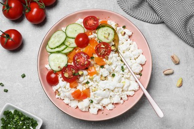 Delicious cottage cheese with vegetables served for breakfast on light grey table, flat lay