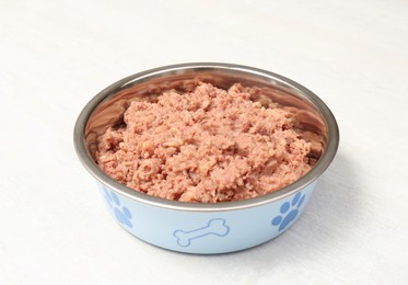 Wet pet food in feeding bowl on white table