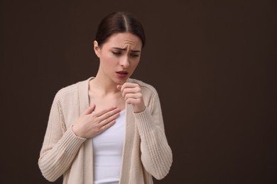 Woman coughing on brown background, space for text. Cold symptoms